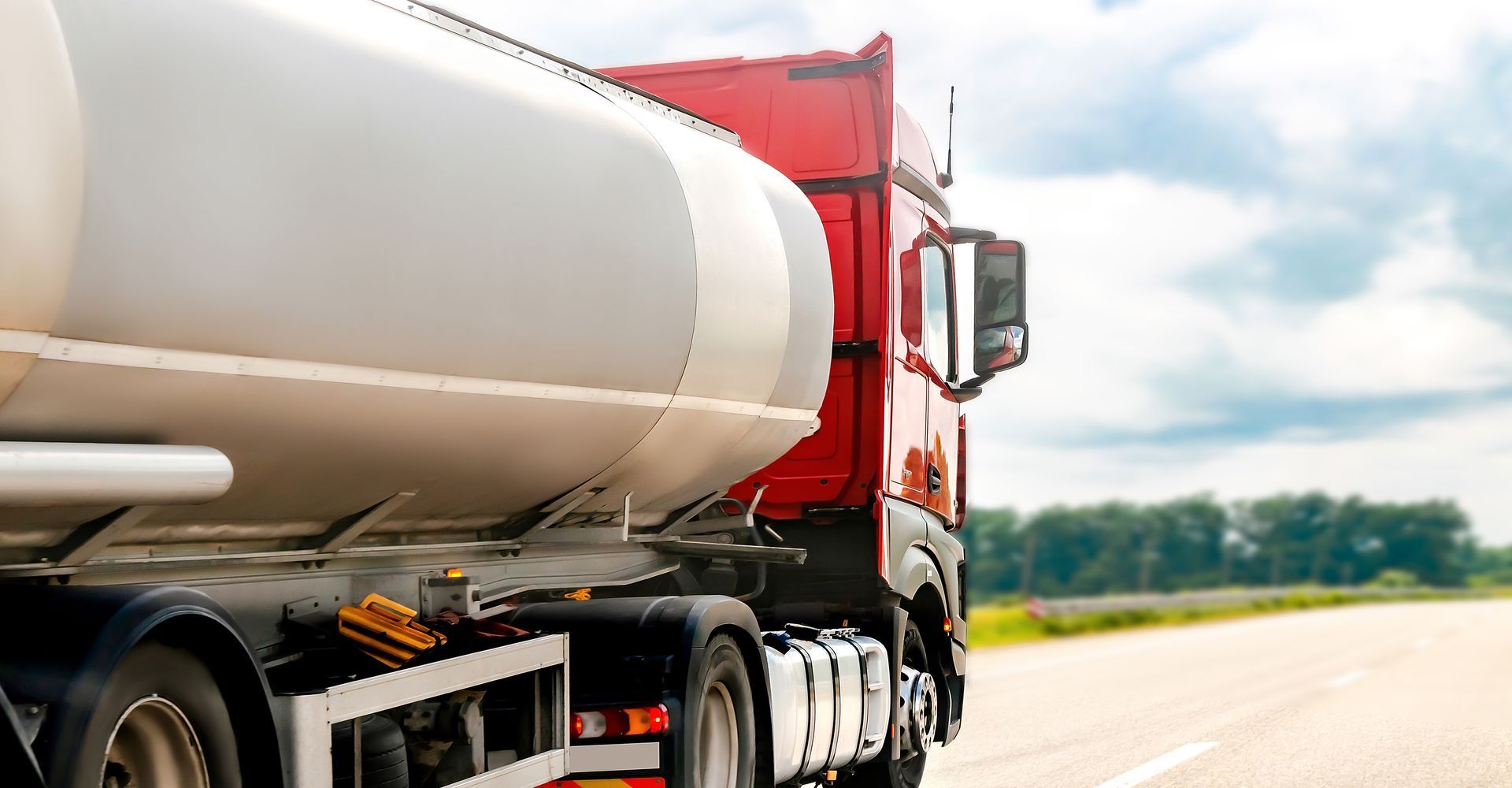 Un camion-citerne circule sur une autoroute bordée de champs ouverts.