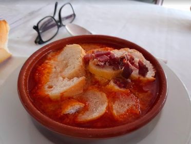 Un tazón de sopa con pan y un par de vasos sobre una mesa.