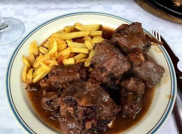 Un plato de carne y patatas fritas en una mesa