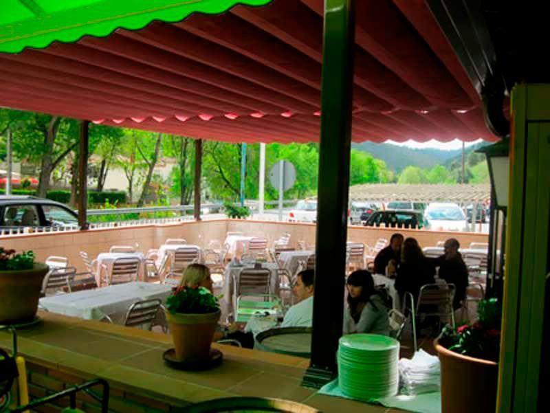 Un restaurante con mesas y sillas bajo un toldo verde.