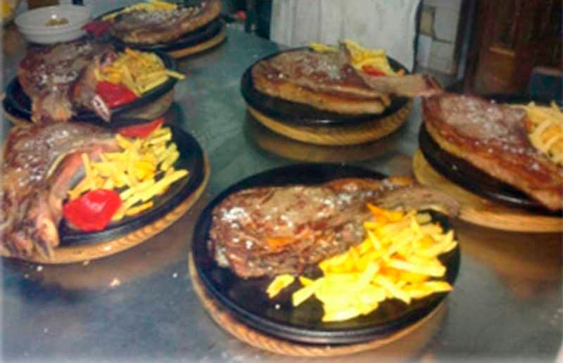 Una mesa cubierta con platos de comida que incluían bistec y papas fritas.