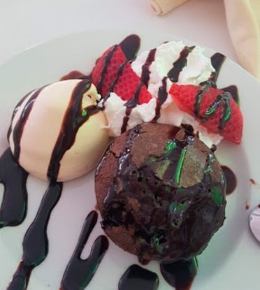Un plato blanco cubierto con helado de brownie y fresas.