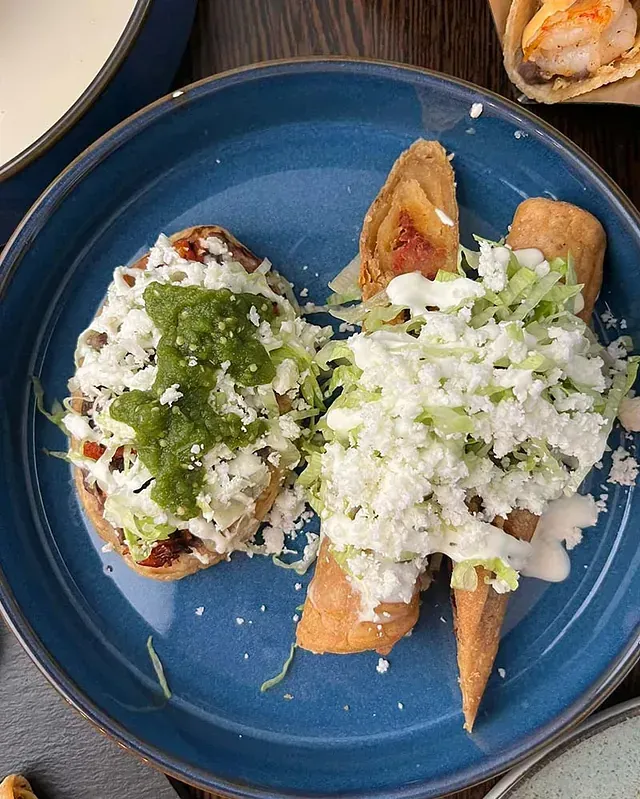 Un primer plano de un plato azul cubierto con comida sobre una mesa.