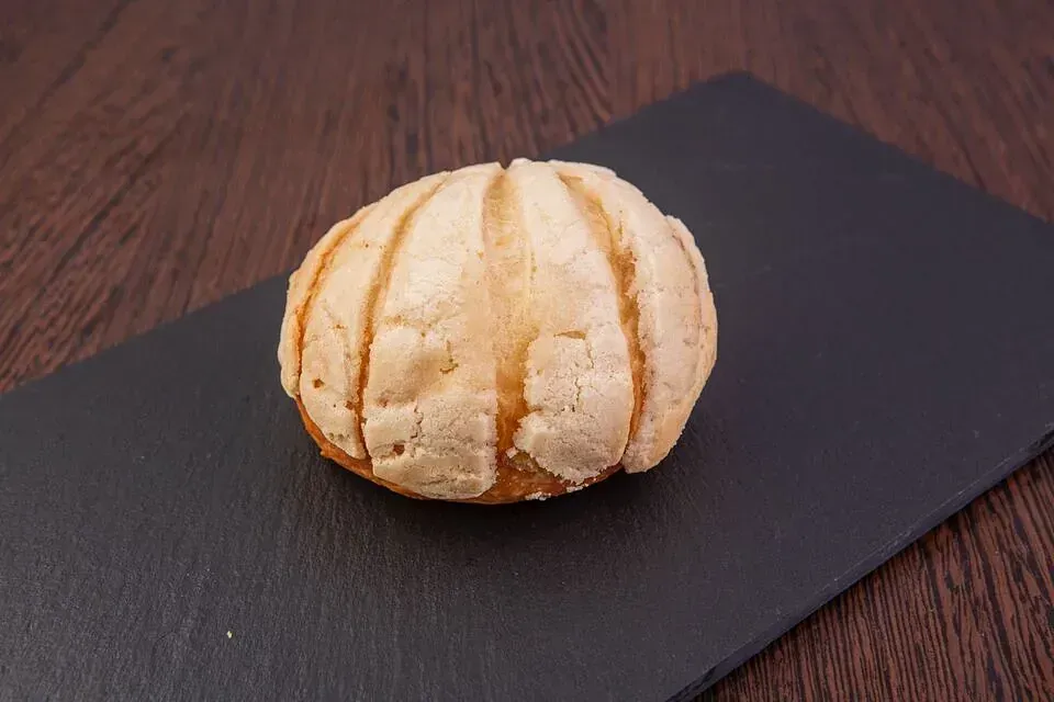 Un pan de concha está sentado sobre una tabla de cortar negra sobre una mesa de madera.