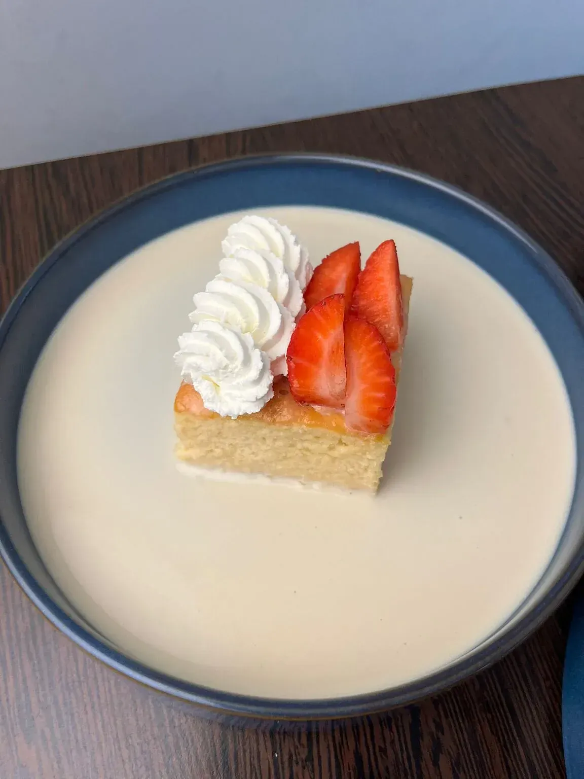 Un trozo de pastel con crema batida y fresas en un plato.