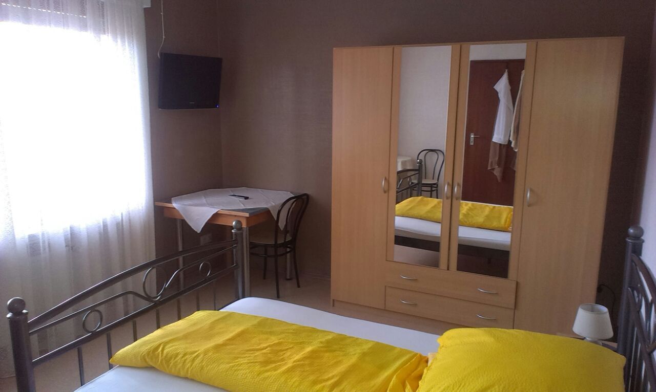 Ein Schlafzimmer mit Bett, Kleiderschrank, Tisch und Stühlen.