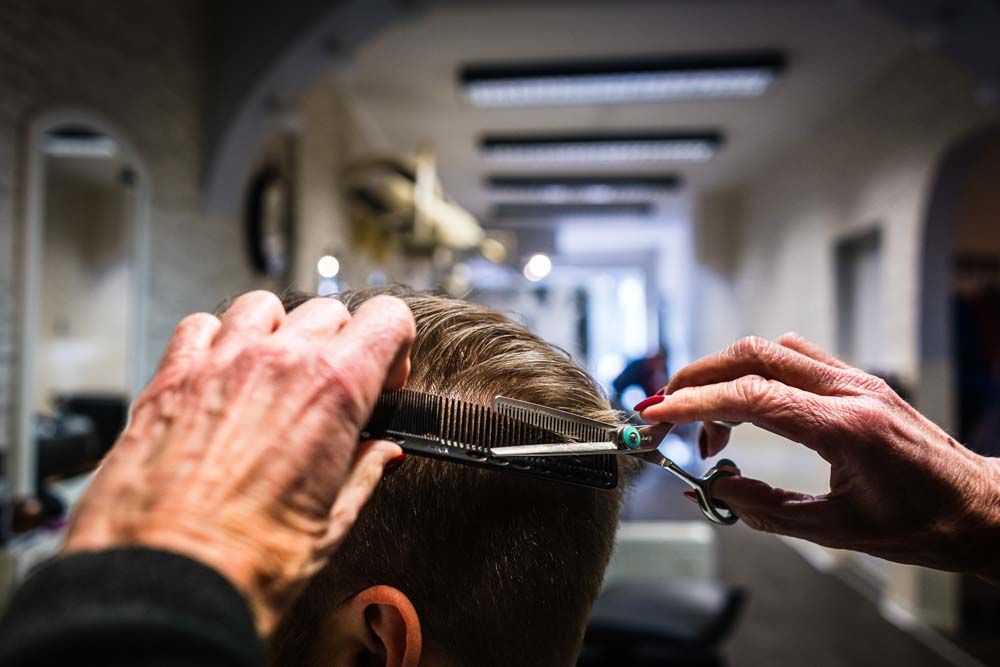 Ein Mann lässt sich in einem Salon von einem Friseur die Haare schneiden.