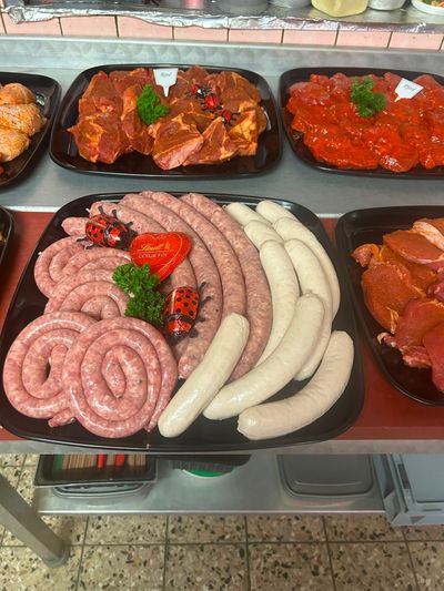 Zwei rohe Rindersteaks auf einem Holzbrett mit Kräutern und Kirschtomaten vor dunklem Hintergrund