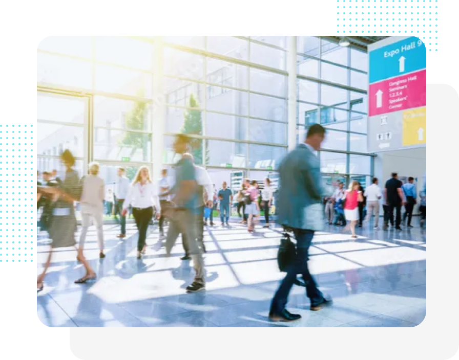 Menschen gehen in einem hellen, modernen Gebäude mit großen Fenstern. Ein Schild weist in Richtung Expo Hall.