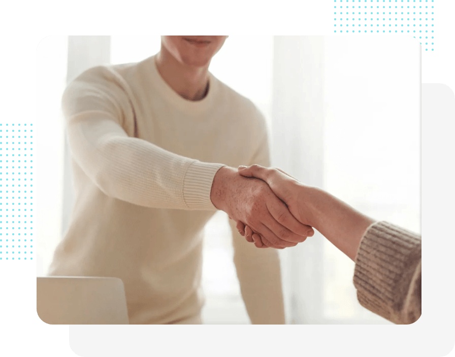 Eine Person in einem beigen Pullover schüttelt jemandem die Hand, wahrscheinlich um einen Geschäftsabschluss zu beschließen oder um sich in einem Büro zu begrüßen.