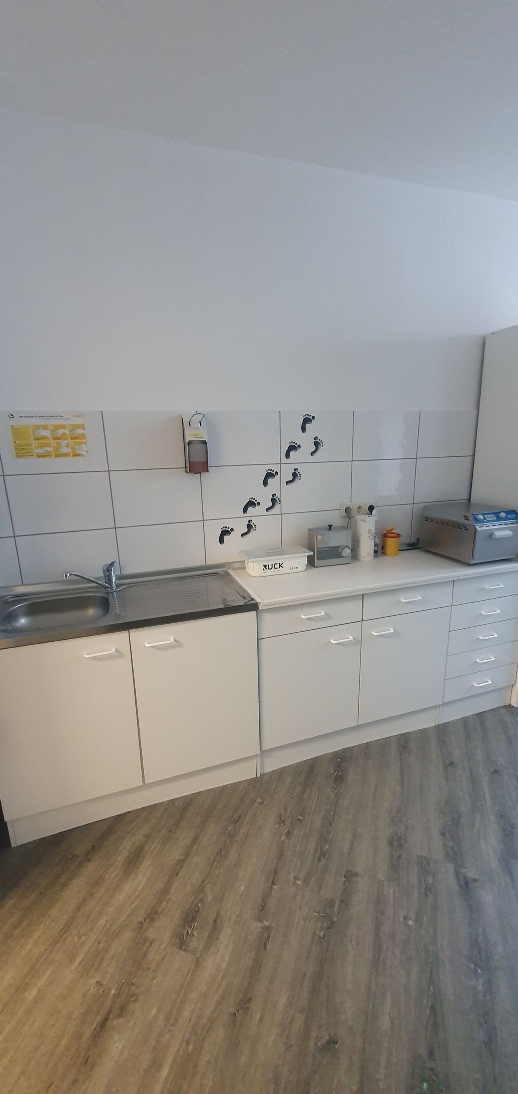 eine Küche mit weißen Schränken , einem Waschbecken und einem Holzboden