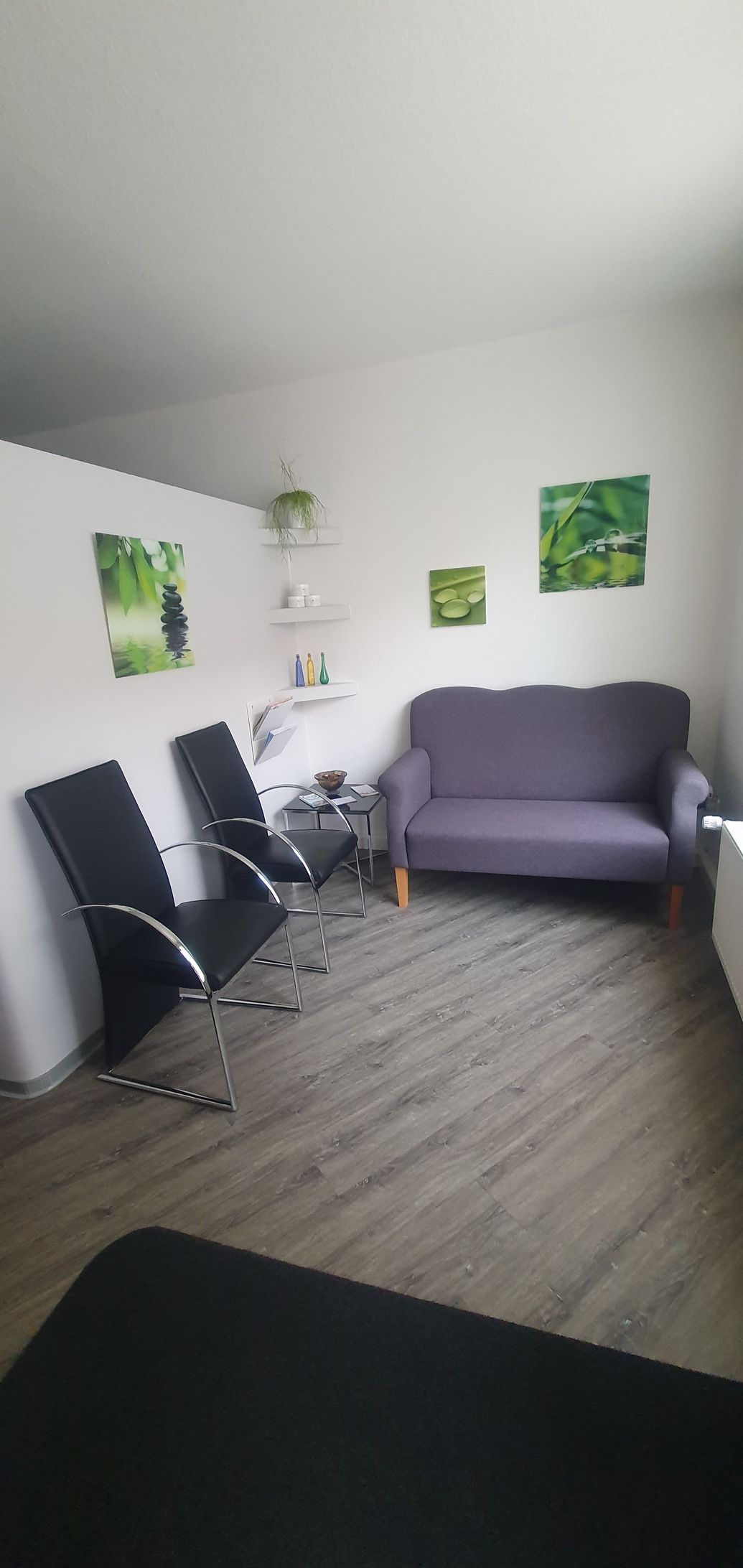 ein Wohnzimmer mit einer lila Couch und zwei schwarzen Stühlen