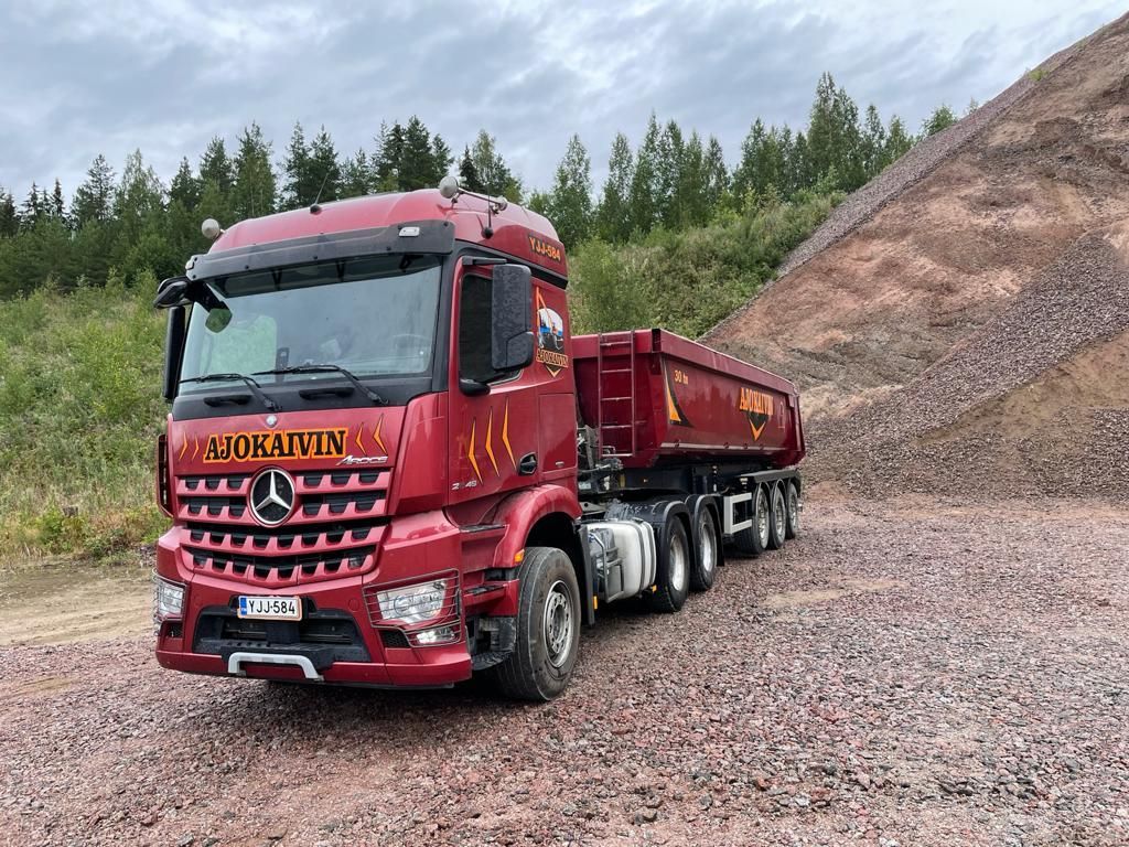 Punainen kippiauto pysäköitynä soralle maakasan viereen metsäaukeamalla