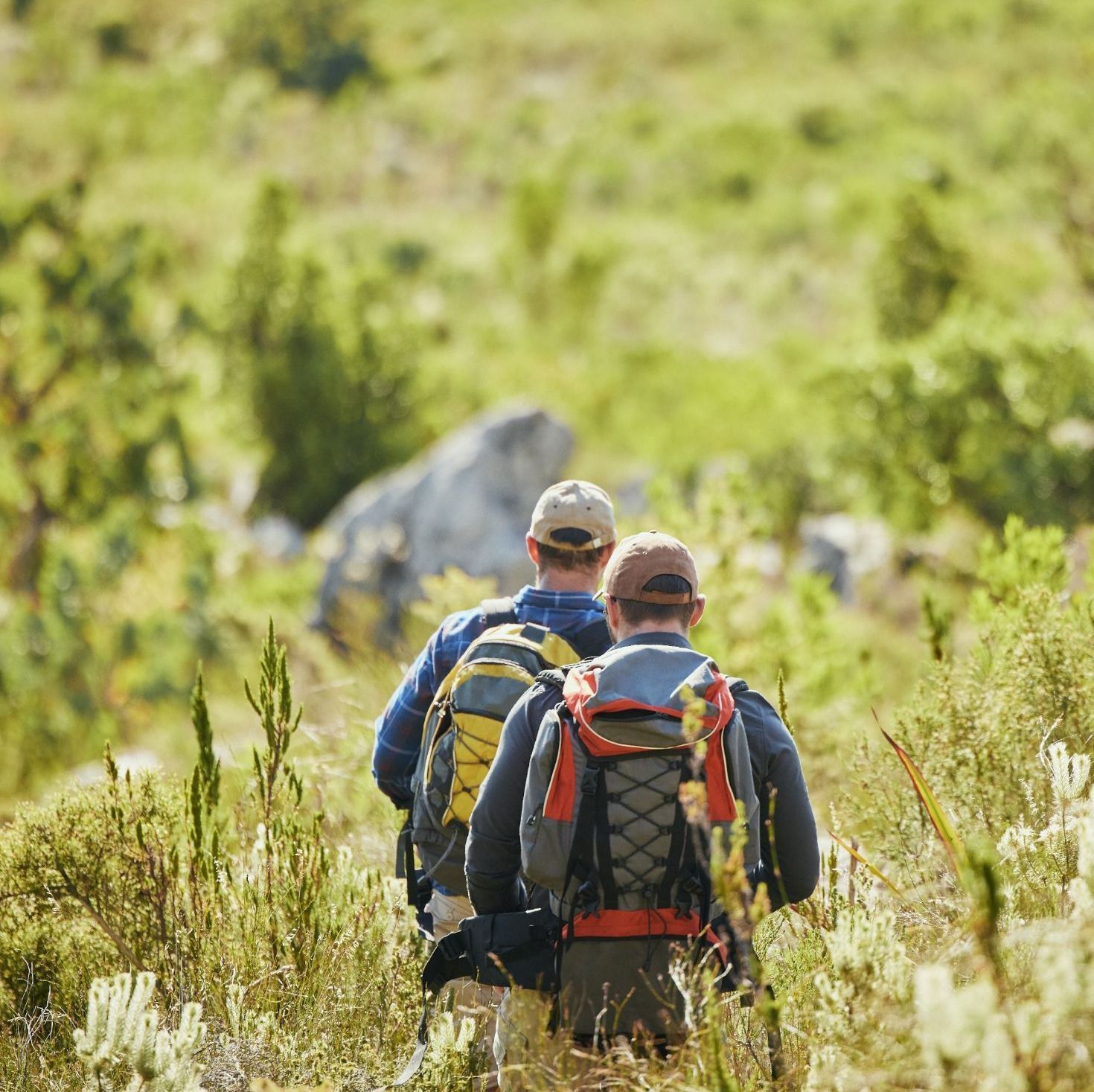Dos hombres con mochilas caminan por un campo de hierba.