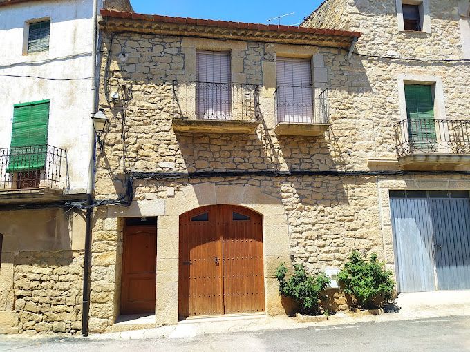 Un edificio de piedra con balcón y puerta de madera.