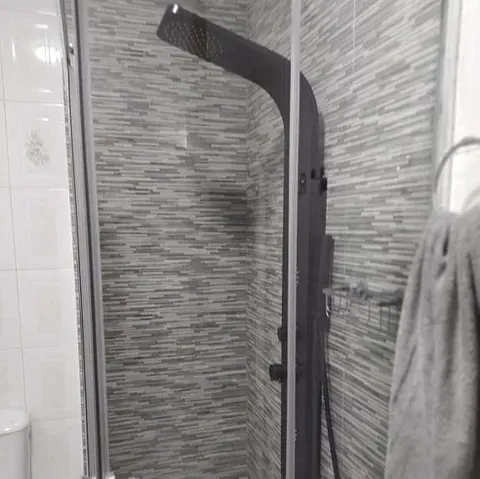 Una fotografía en blanco y negro de una ducha en un baño.