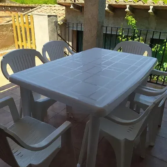 Una mesa y sillas de plástico blanco en un balcón.
