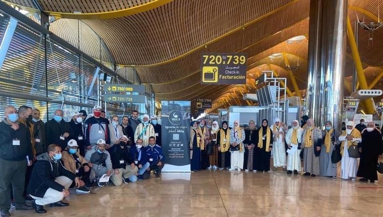 Grupo de personas en una terminal de aeropuerto, algunas con atuendos religiosos.