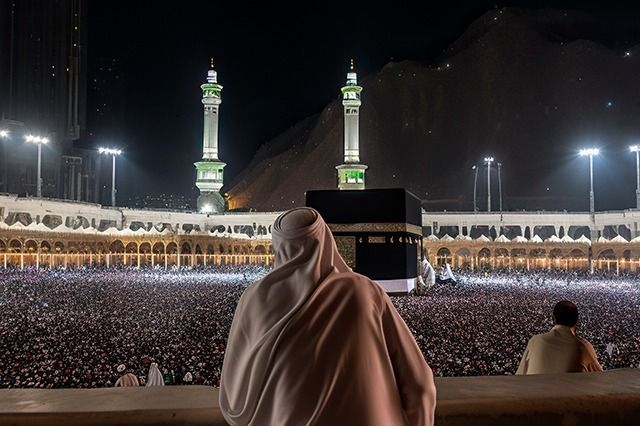 Musulmanes circunvalando la Kaaba de noche en La Meca, Arabia Saudita, bajo luces brillantes.