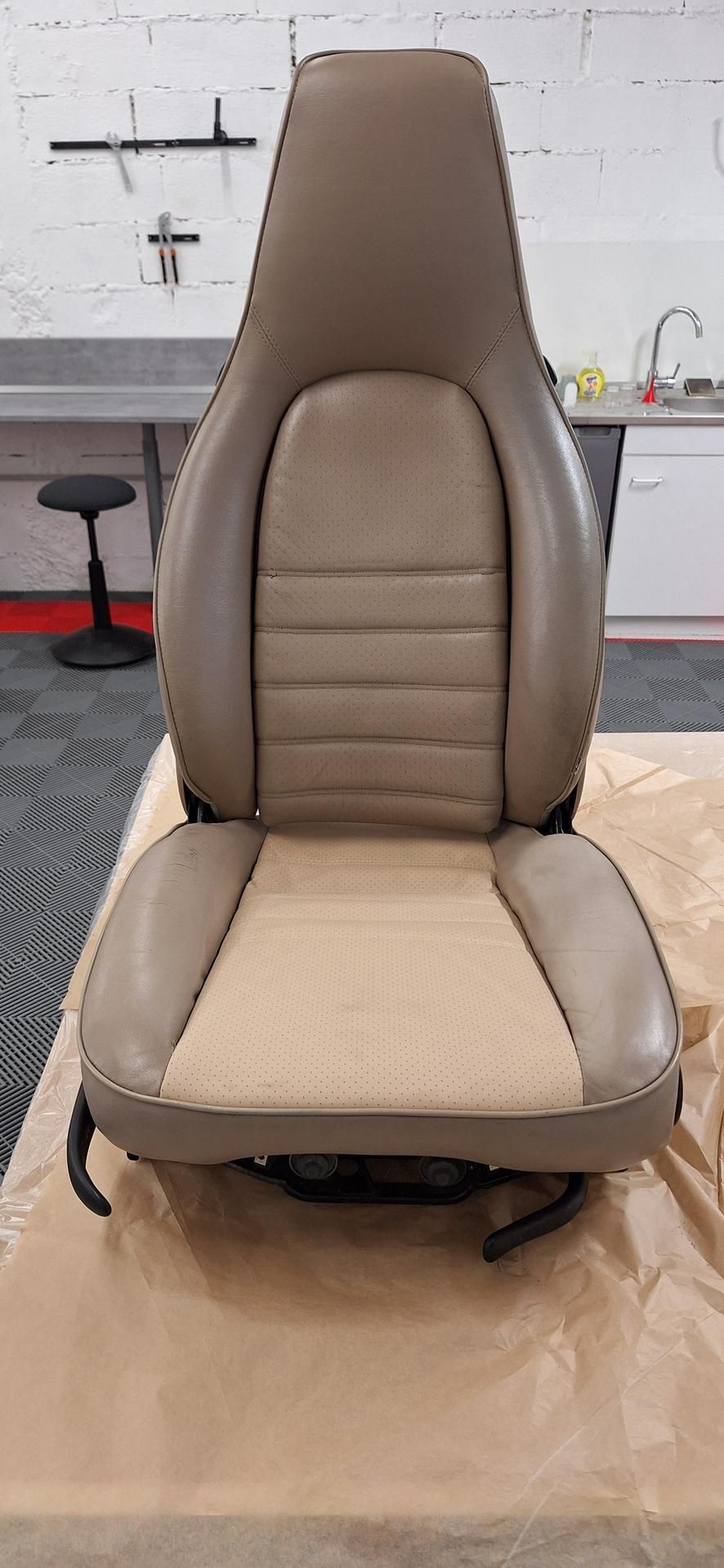 Siège auto beige et beige avec extérieur en cuir, en intérieur.