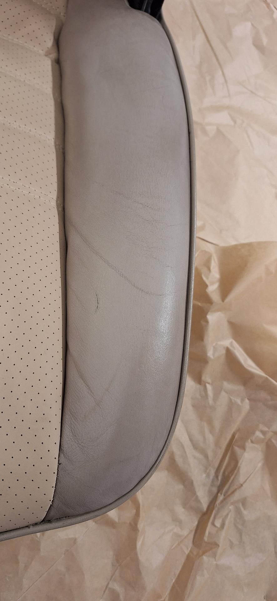 Gros plan sur un article en cuir gris pâle à côté d'un article blanc perforé, sur du papier brun.