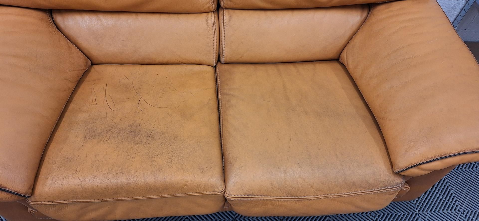 Canapé en cuir beige avec tache sur le coussin d'assise gauche.