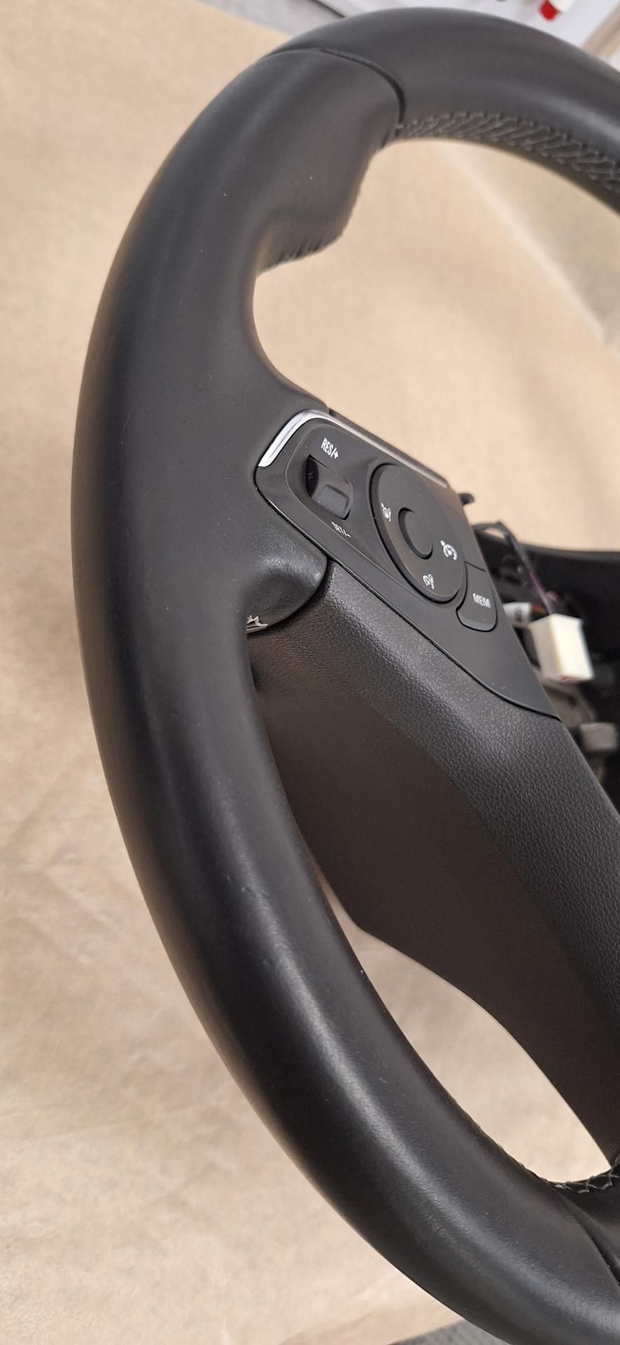 Gros plan sur un volant de voiture noir avec des boutons de commande.