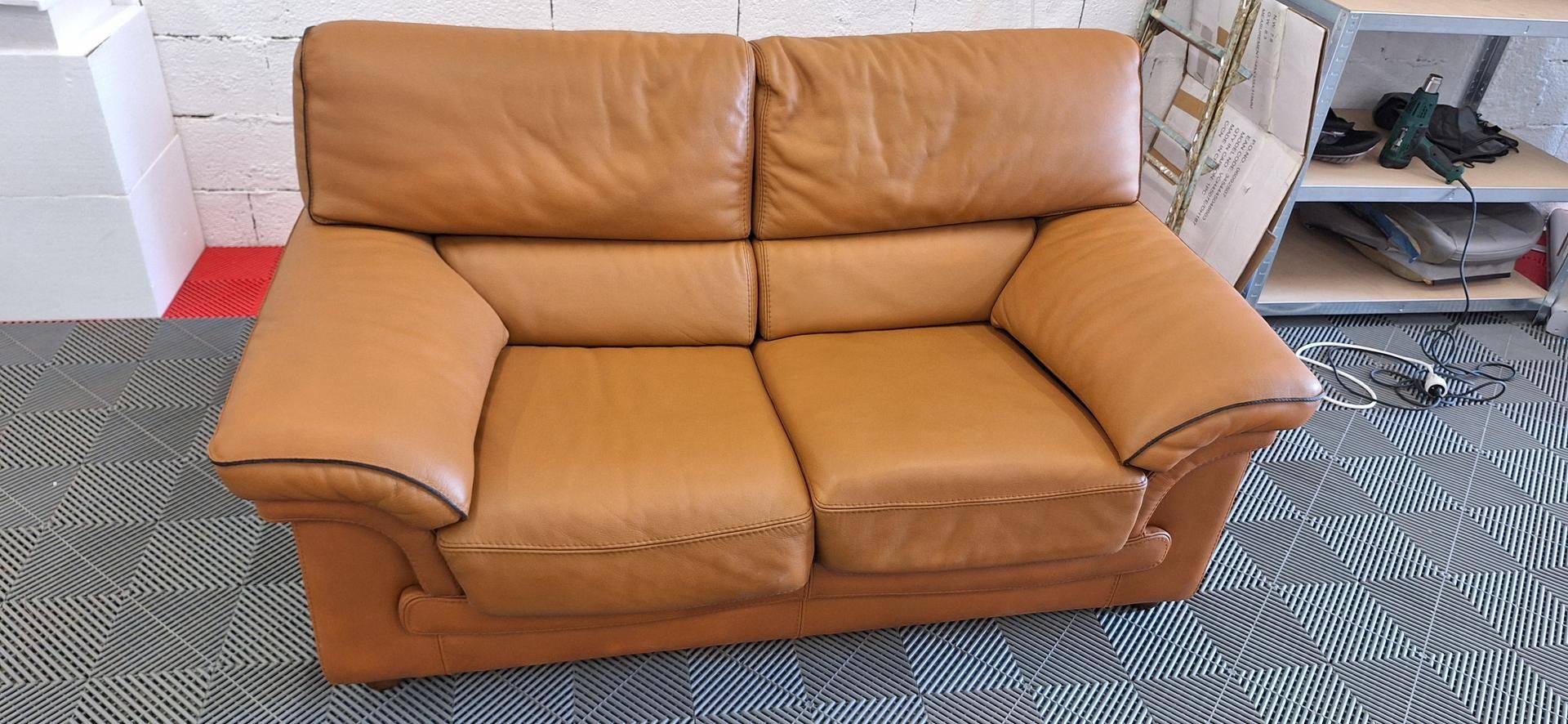 Canapé en cuir marron sur un tapis à motifs, dans un décor intérieur.