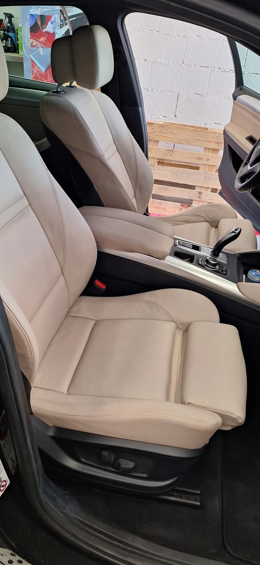 Sièges de voiture en cuir beige à l'intérieur d'un véhicule, montrant les commandes de réglage des sièges.