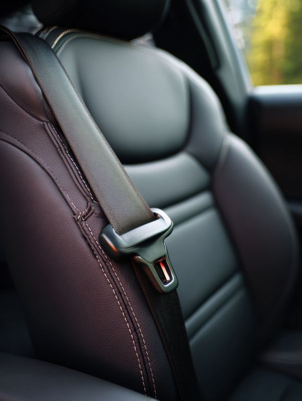 Gros plan sur un siège de voiture en cuir noir avec une ceinture de sécurité attachée.