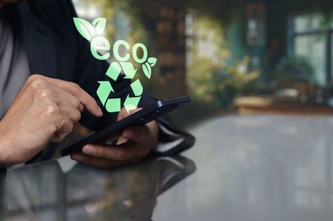 Smartphone tenu entre deux mains avec un logo recyclage au-dessus