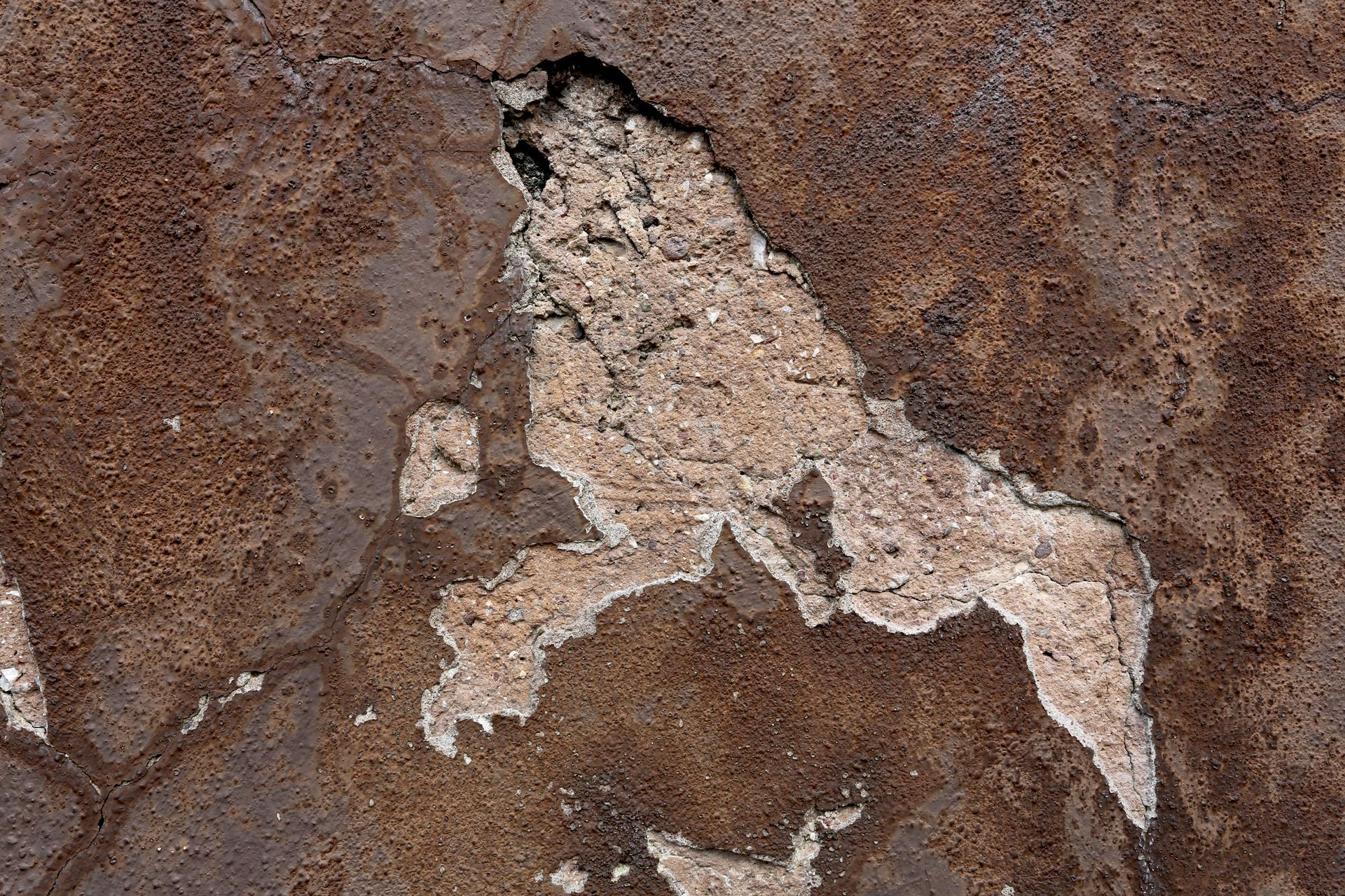 Mur texturé brun et beige avec un grand trou irrégulier révélant un intérieur plus clair.