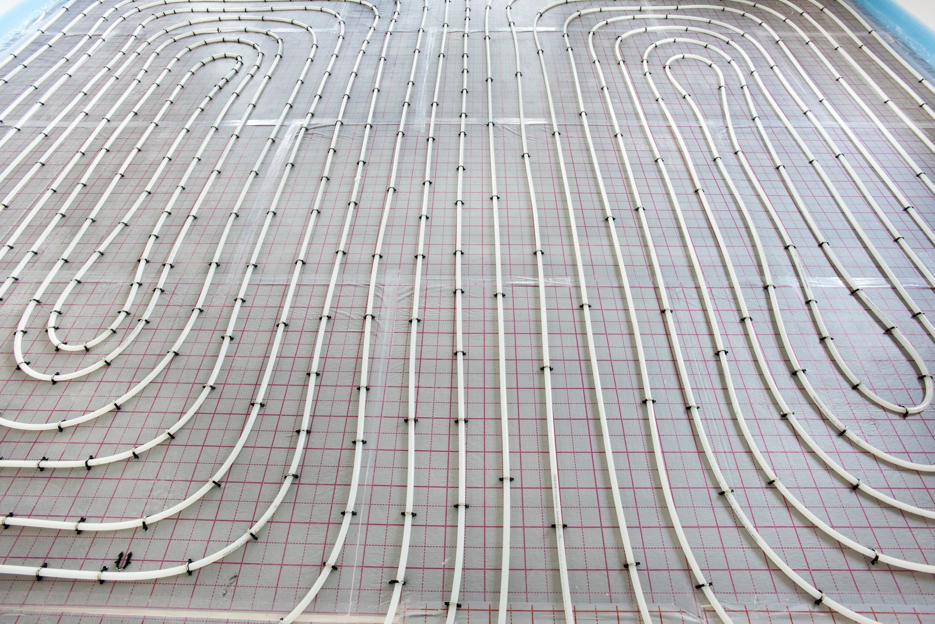 Installation d'un système de chauffage au sol radiant avec tuyaux enroulés, disposition en grille.