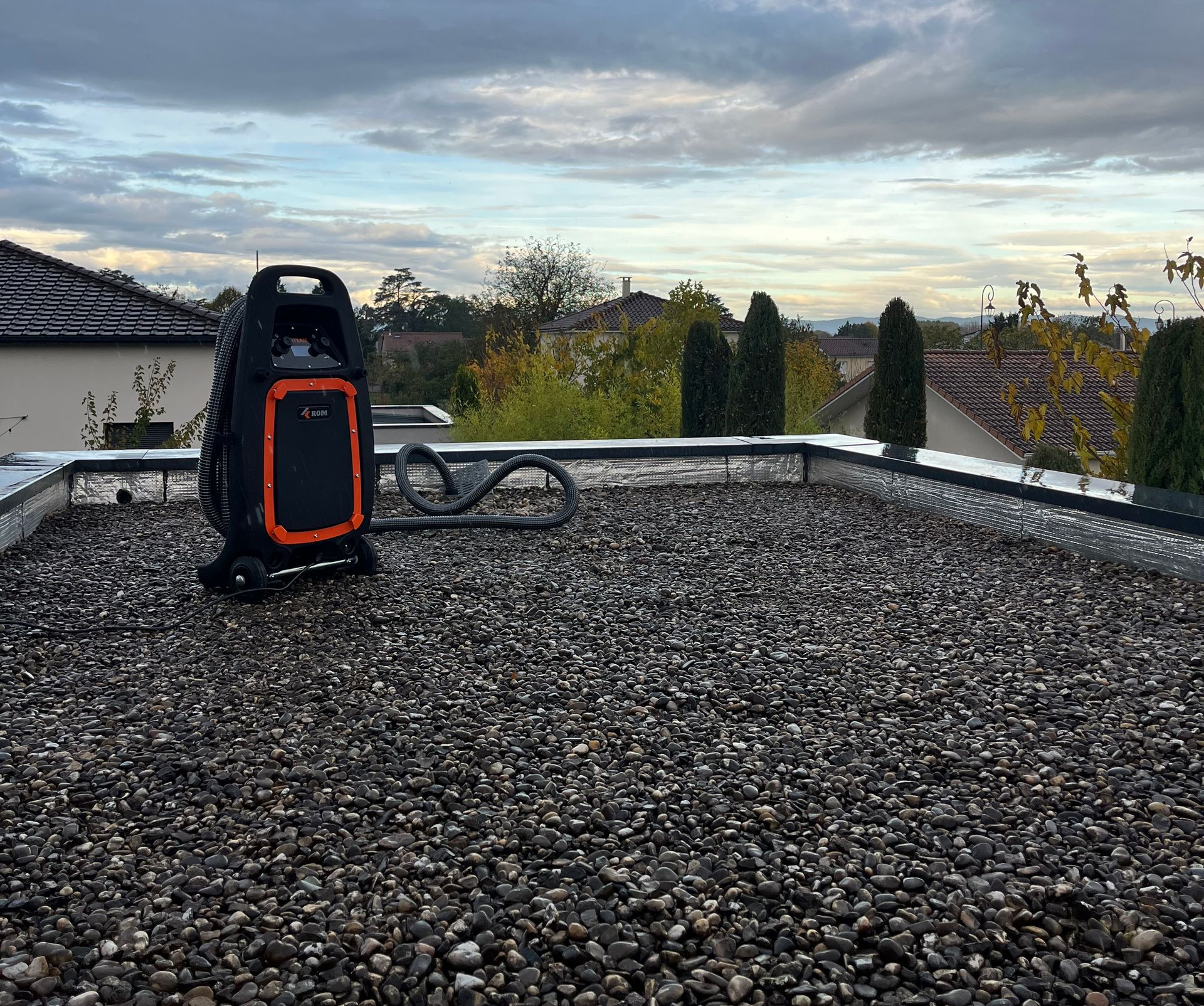Matériel de recherche de fuite sur un toit de gravier, avec un ciel nuageux en arrière-plan.