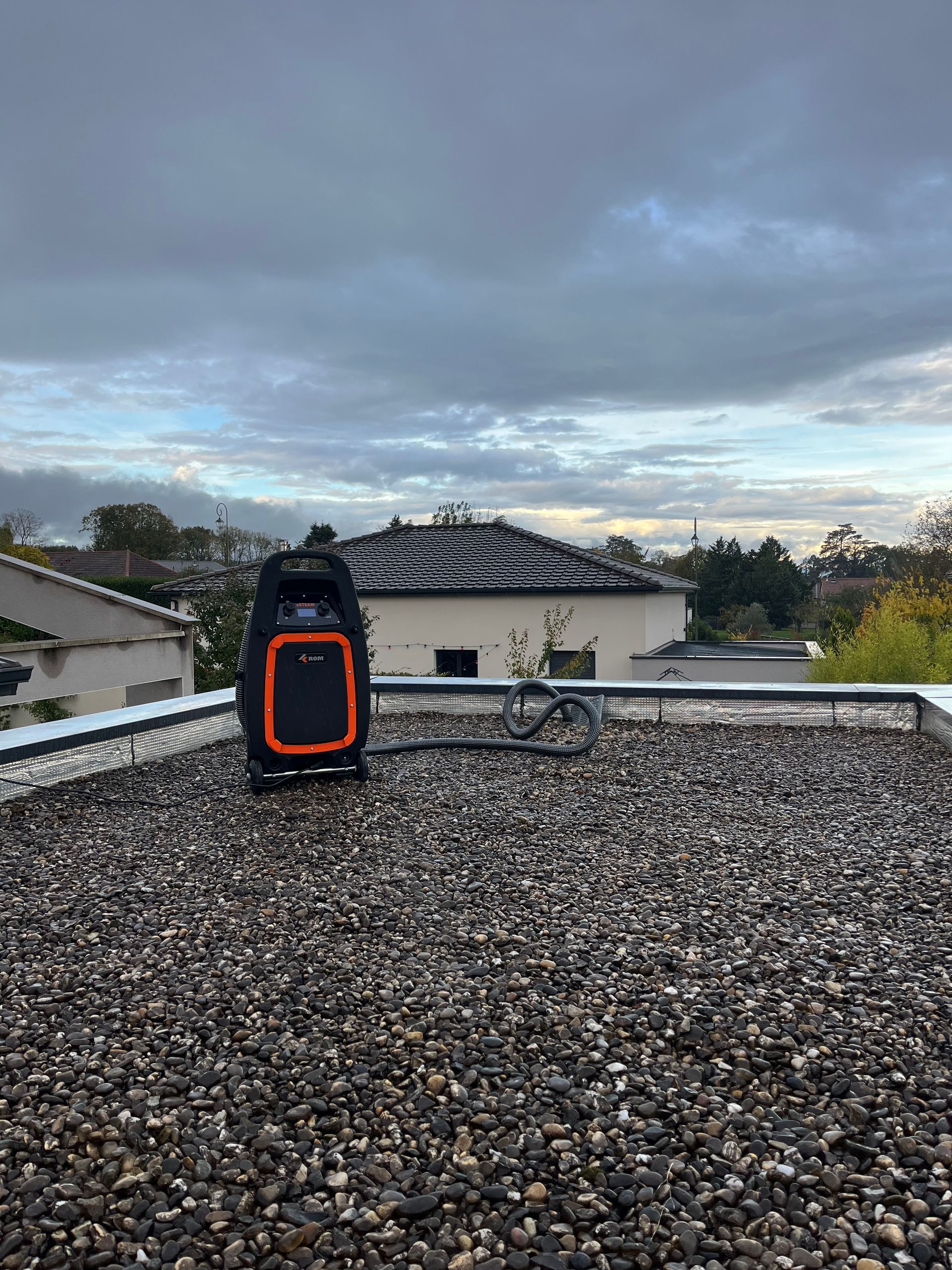 Matériel de recherche de fuite sur un toit plat en gravier, ciel nuageux en arrière-plan.