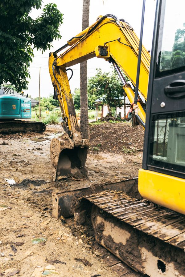 Excavatrice jaune creusant dans la terre.
