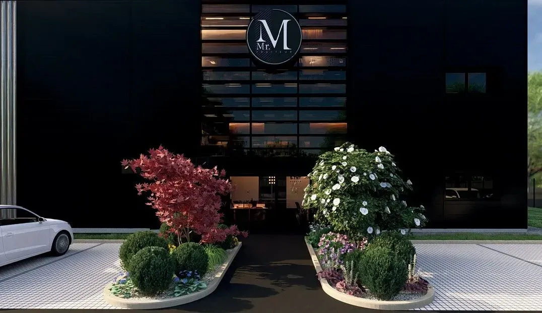 Entrée d'un bâtiment avec une façade noire, des plantes et une voiture ; logo au-dessus de l'entrée.