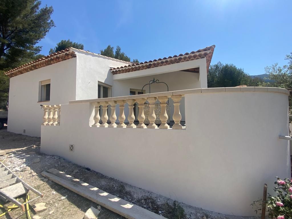 Maison avec façade blanche, muret de clôture avec colonnes décoratives