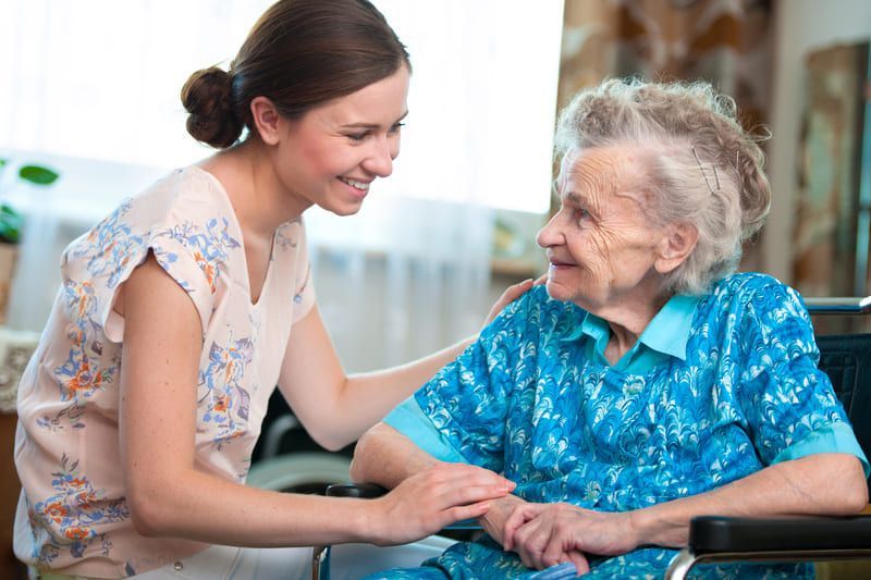 Eine junge Frau kümmert sich um eine ältere Frau im Rollstuhl | Ambulanter Pflegedienst Rotenburg