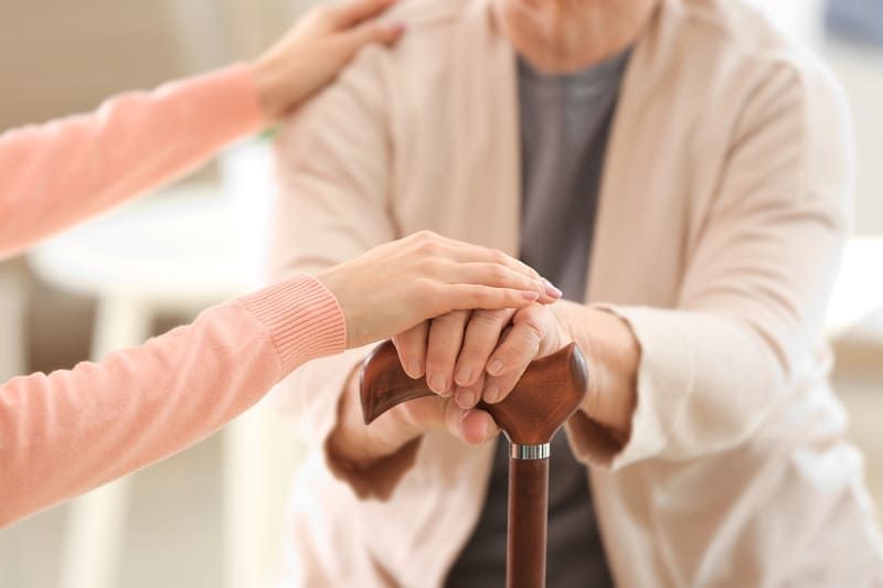 Eine Frau hält die Hand einer älteren Frau, die einen Gehstock hält | Ambulanter Pflegedienst Rotenburg