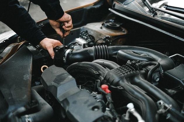 Un hombre está trabajando en el motor de un coche.