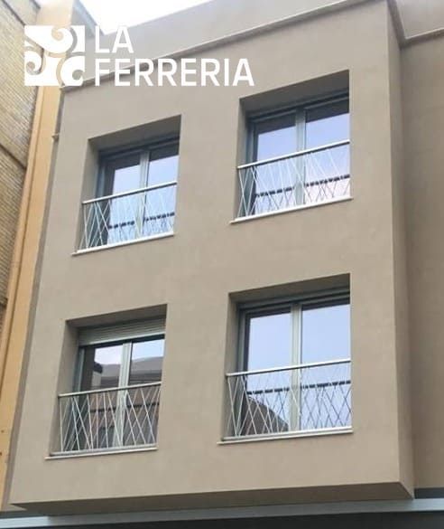 Fachada moderna de edificio de apartamentos de color beige con cuatro ventanas y barandillas blancas, marca de agua de La Ferreria en la esquina.