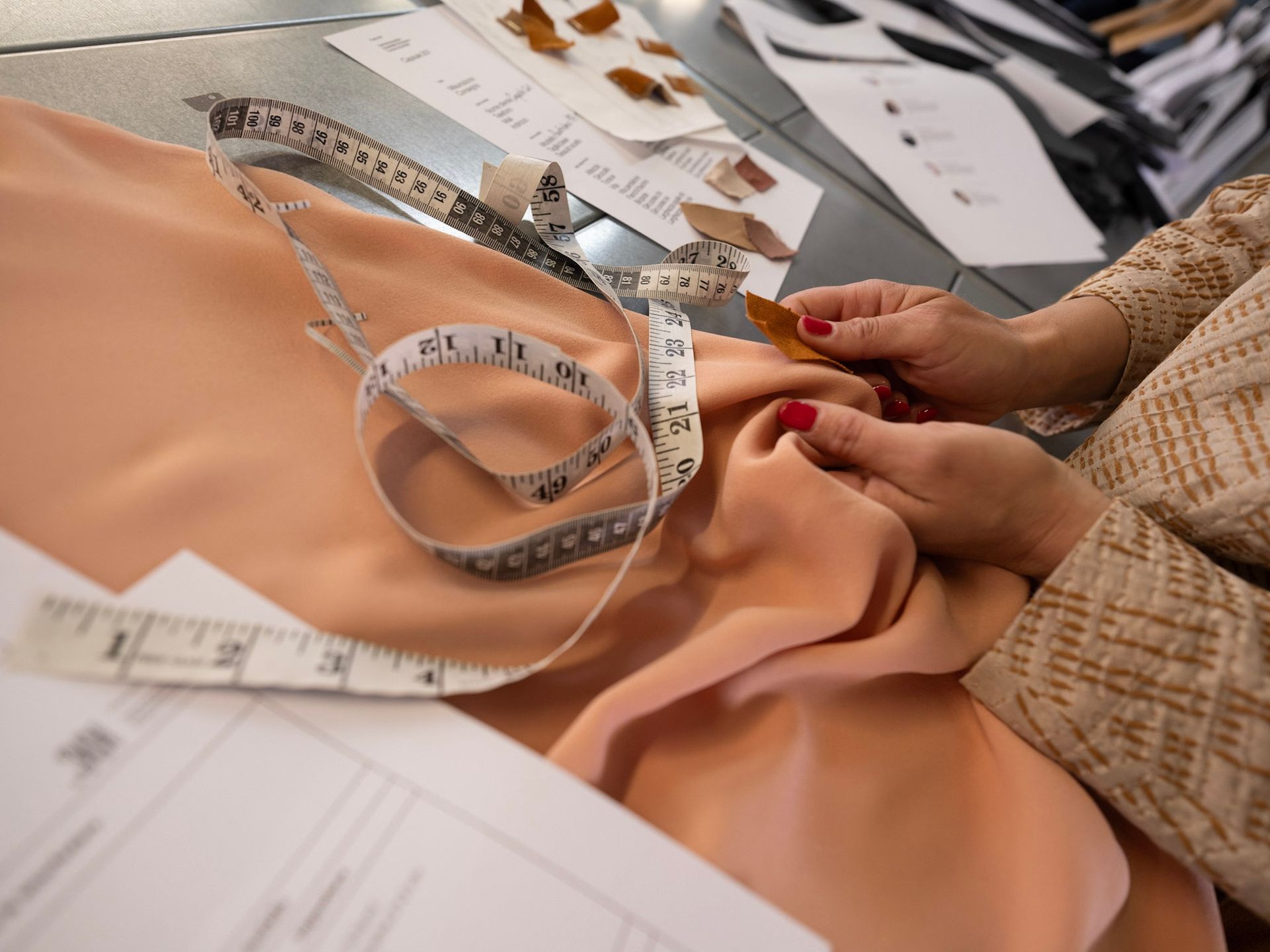 Rocchetti di filo in varie tonalità di rosso, rosa e arancione disposti su uno scaffale di metallo.