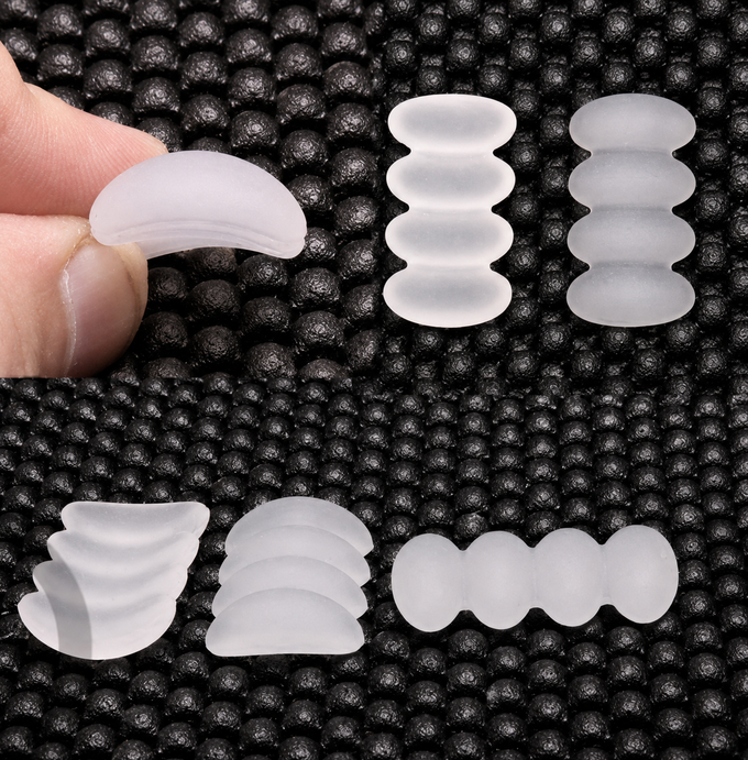 Primer plano de protectores de silicona blanca translúcida de varias formas, colocados junto a una alfombrilla