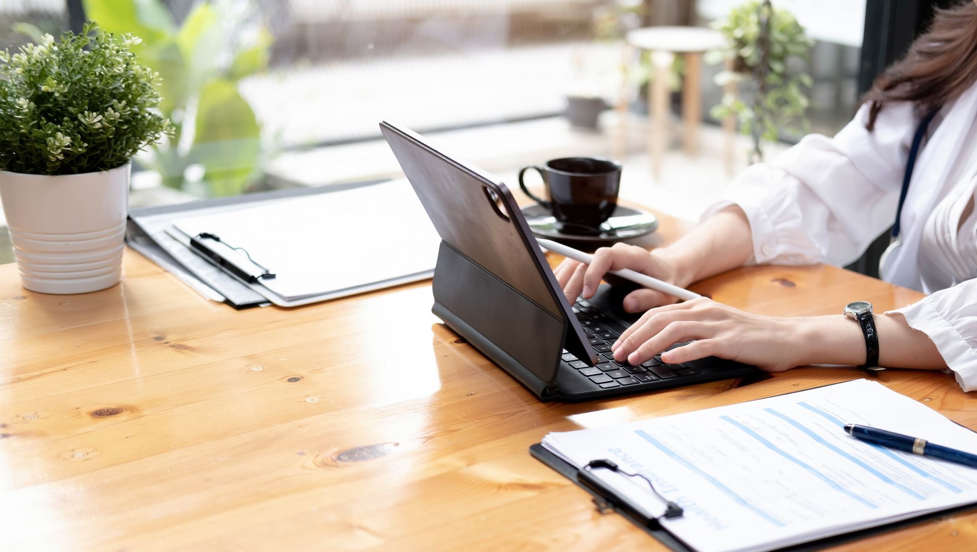 Une femme tape sur un ordinateur portable posé sur un bureau en bois.