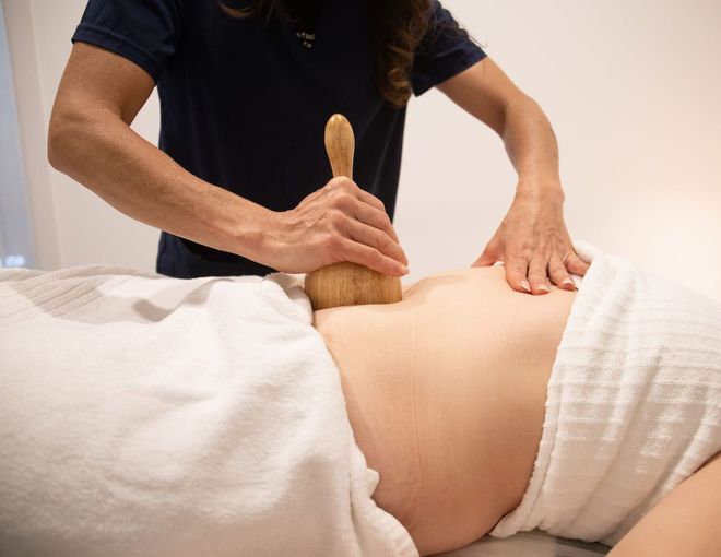 Una mujer está recibiendo un masaje con un rodillo de madera.