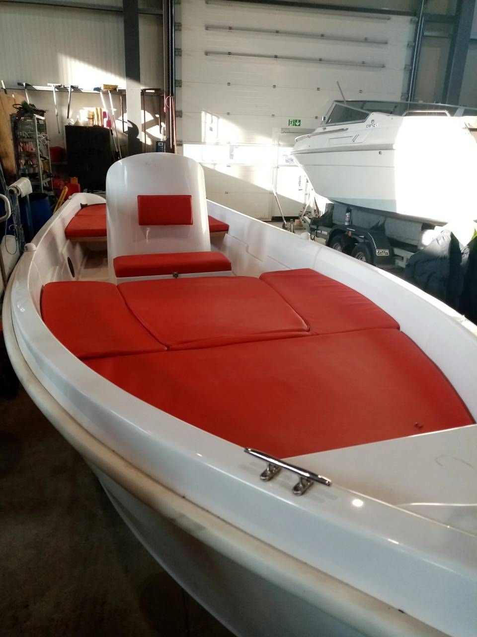Motoscafo bianco e rosso in un garage, visto dalla prua.