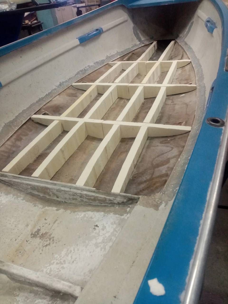 Interno di una barca blu con struttura in legno bianco in fase di costruzione