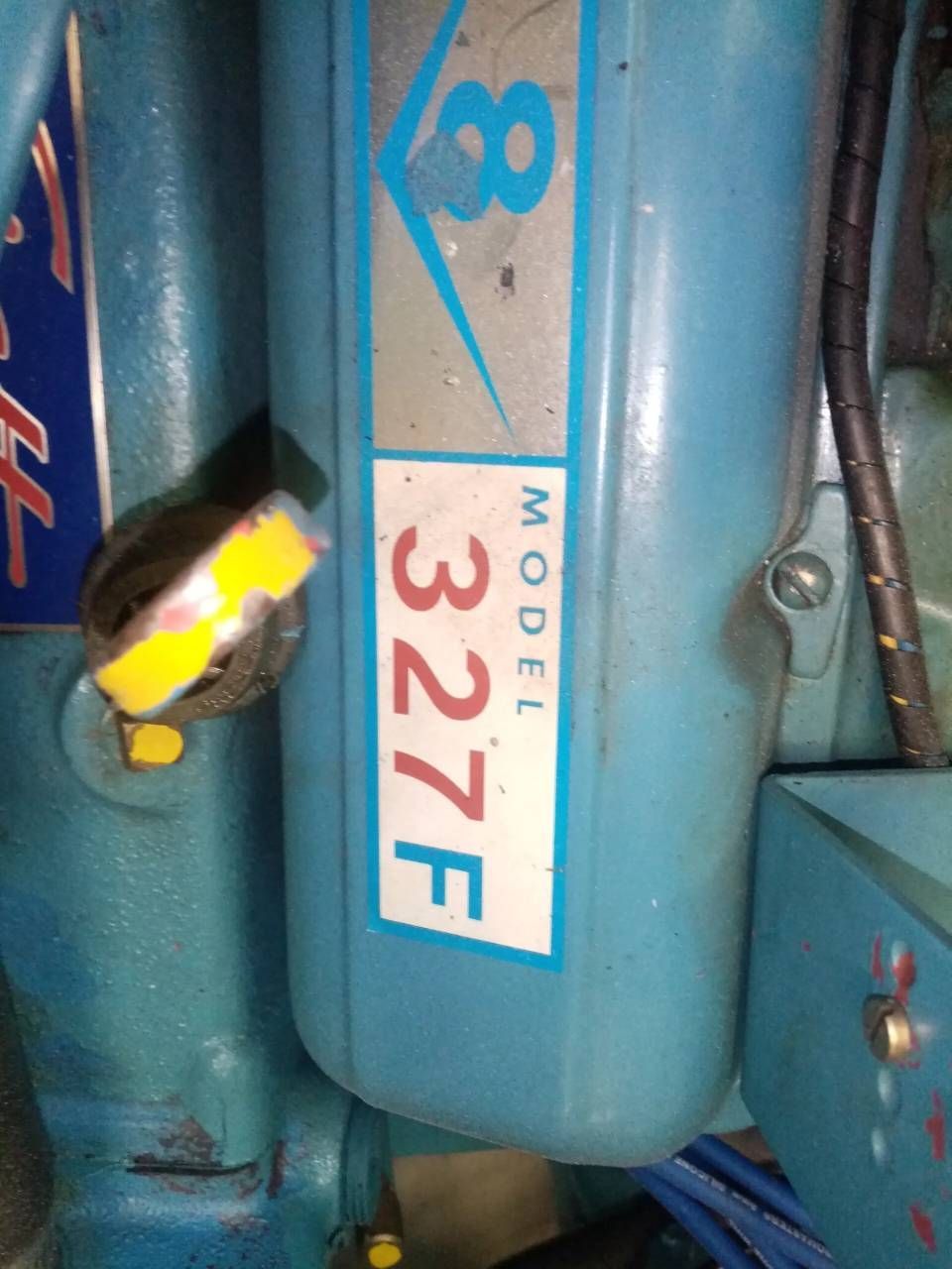 Primo piano di un serbatoio di carburante blu per motocicletta con il numero 327F e una manopola gialla nelle vicinanze.