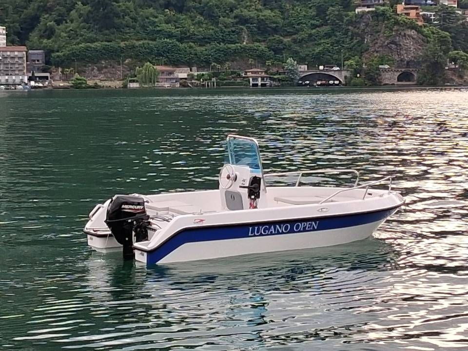 Barca di salvataggio bianca e blu su acque calme vicino a una costa verdeggiante